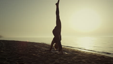 Deportista-Practicando-Yoga-Posan-En-La-Playa-Al-Amanecer.-Chica-Estirándose.