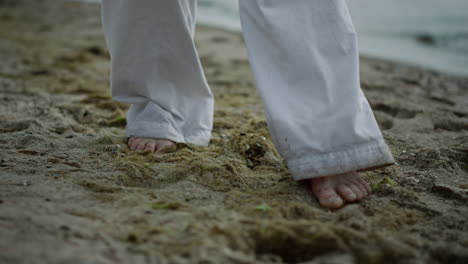 Unknown-barefoot-man-stepping-on-beach-closeup.-Athlete-exercising-on-seacoast