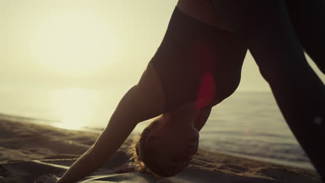 Fit-sportswoman-bending-body-standing-yoga-asana-on-sandy-beach-close-up.