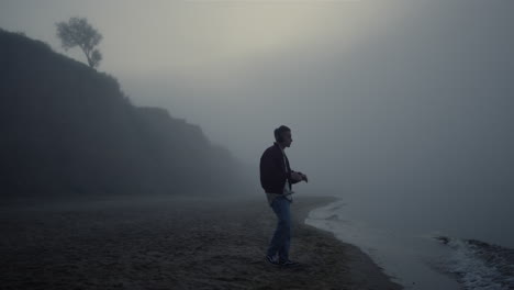 Relaxed-man-headphones-standing-on-foggy-beach.-Guy-listening-music-in-earphones