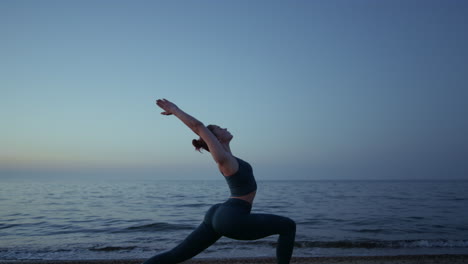 Flexible-girl-doing-warrior-asana-raising-hands-to-sky.-Woman-standing-yoga-pose