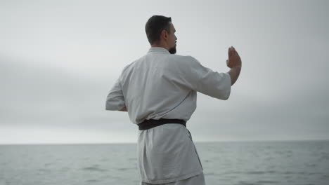 Sportler-übt-Handpositionstraining-Karate-In-Der-Nähe-Des-Meeres.-Mann-Lernt-Technik
