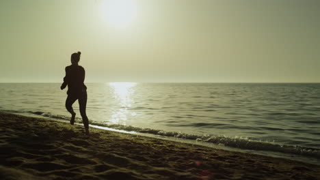 Fast-woman-running-alone-sand-beach-at-sunset.-Silhouette-girl-jogging-near-sea