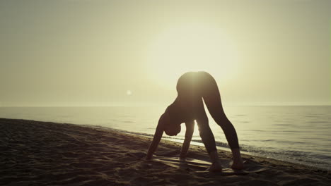 Silhouette-yoga-woman-exercising-on-beach.-Girl-training-flexibility-at-sunset.