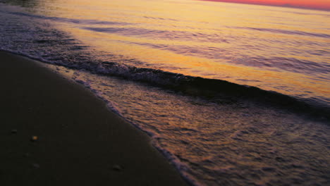 Closeup-sea-waves-splashing-sandy-beach-in-cold-evening-sunset-dusk-slow-motion