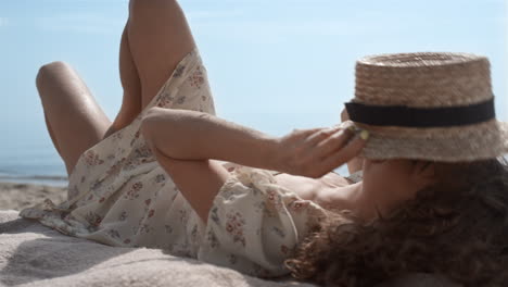 Relaxed-girl-covering-face-with-straw-hat-lying-on-beach-close-up.-Woman-relax-.