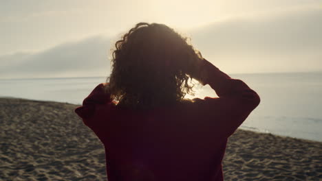 Stylish-girl-walking-on-sea-shore-in-morning.-Woman-enjoying-sunrise-lights