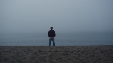Thoughtful-guy-standing-sea-beach.-Relaxed-man-enjoying-morning-ocean-landscape