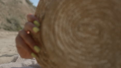 Positive-girl-playing-beach-covering-camera-with-hat-close-up.-Woman-lying-sand.