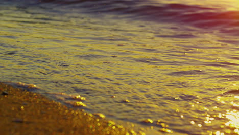 Meereswellen-Plätschern-Am-Goldenen-Sandstrand.-Wasseroberfläche,-Die-Gelben-Sonnenuntergang-Reflektiert