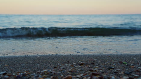 Closeup-sea-water-waves-splashing-sandy-beach-evening.-Sand-beach-macro