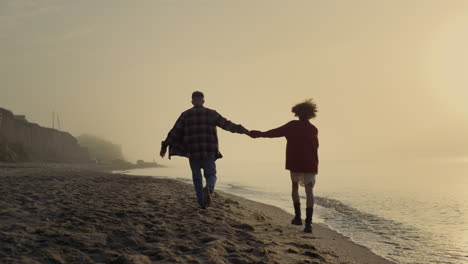 Loving-couple-walking-on-beach.-Happy-girl-and-guy-enjoying-summer-sunset-at-sea