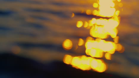 Defocused-ocean-waves-splashing-golden-sand-beach.-Orange-sunset-reflection