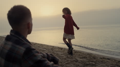 Happy-couple-enjoying-sunrise-at-ocean-beach.-Positive-girl-dancing-on-sea-shore