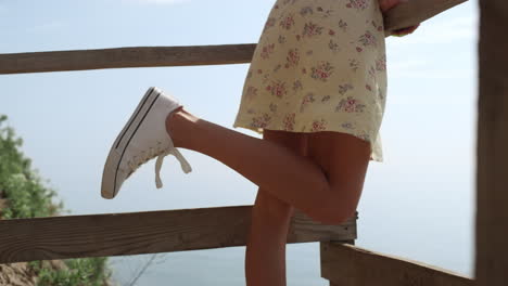 Unknown-woman-feet-standing-stairs-platform-on-sunny-beach.-Lagy-raising-one-leg