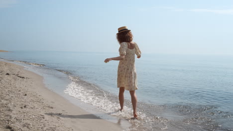Cheerful-girl-running-ocean-waves-back-view.-Playful-woman-walking-wet-sand.