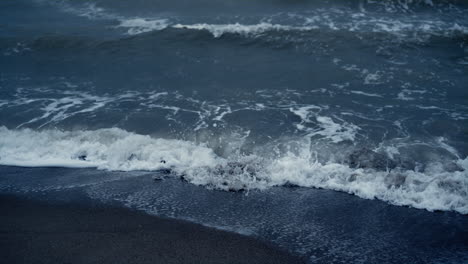 Blaue-Meeresflut-Stürmt-Den-Strand-Von-Island.-Meereswellenschaum,-Der-Sandufer-Natur-Kracht