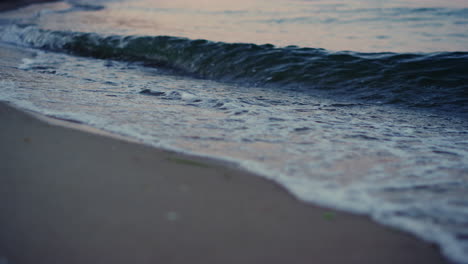Close-up-blue-cold-ocean-waves-breaking-sandy-beach-in-morning-dawn