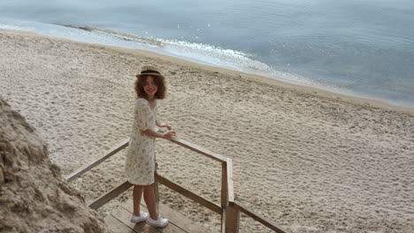 Elegant-lady-standing-stairs-platform-watching-beach-beauty.-Girl-smiling-camera