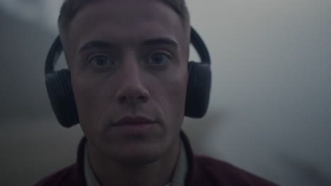 Handsome-guy-listening-music-in-headphones.-Closeup-focused-man-posing-at-camera