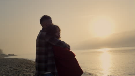 Romantic-woman-and-man-standing-on-beach-at-sunrise.-Couple-enjoying-sea-view