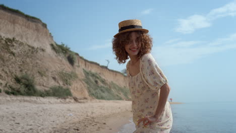 Cute-curly-girl-dancing-on-ocean-waves-holding-dress.-Smiling-woman-have-fun.