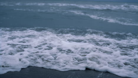 Ocean-waves-storming-beach-in-dark-blue-background.-Dangerous-nature-concept.