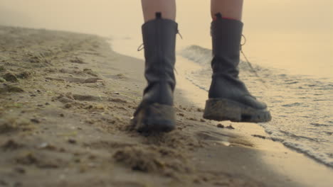 Closeup-woman-legs-dancing-on-sandy-beach.-Girl-feet-wearing-stylish-boots
