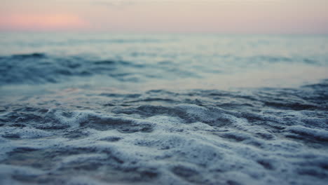 Blue-sea-waves-splashing-sand-seashore-at-cold-morning-sunrise.-Calm-ocean-water