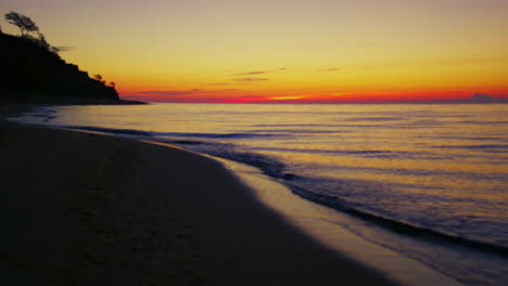 Seeküste-Bei-Orangefarbenem-Sonnenuntergang.-Dunkler-Meeresstrand-Mit-Bergsilhouette