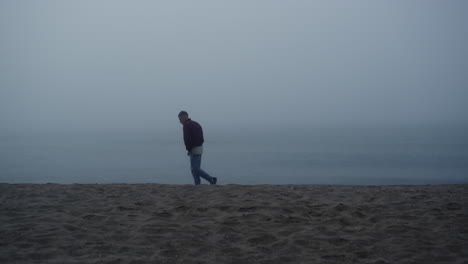 Dreamy-guy-looking-sea-view-in-foggy-morning.-Upset-man-standing-on-sandy-beach