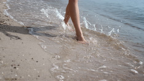 Closeup-woman-legs-walking-wet-sand-near-ocean-waves.-Girl-jumping-on-sea-water.
