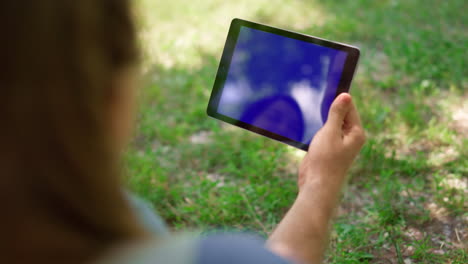 Unknown-hands-holding-tablet-on-nature.-Unrecognizable-man-have-gadget-on-picnic
