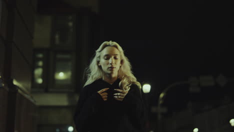 Attractive-girl-walking-city-alone-in-hoodie-at-night-lights-street.