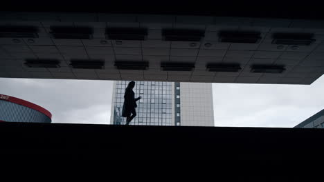 Silhouette-female-person-walking-in-dark-building-at-city-downtown.