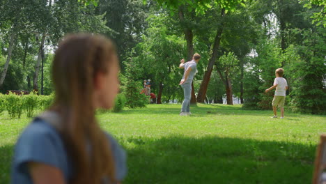 Profile-girl-watching-soccer-game-in-park.-Father-play-football-with-son.