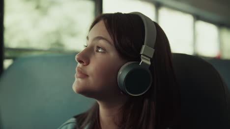 Girl-teenager-traveling-bus-with-headphones-close-up.-Brunette-listening-music.