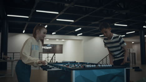 Excited-students-playing-table-football-in-empty-school-lobby-after-classes.