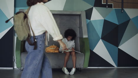 Preteen-schoolgirl-doing-homework-in-hall.-African-american-girl-sitting-bench.