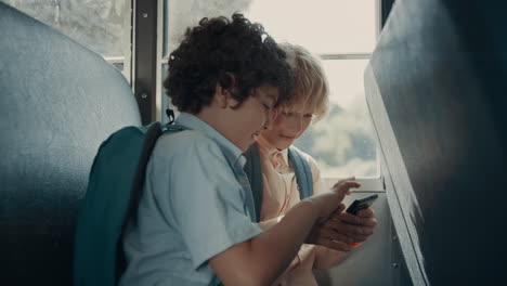 Two-pupils-playing-games-on-phone-sitting-school-bus.-Boys-using-smartphone.