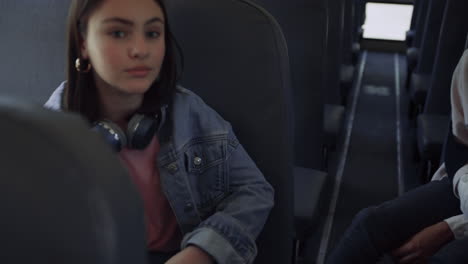 Cute-brunette-schoolgirl-communicating-with-friends-in-school-bus-close-up.