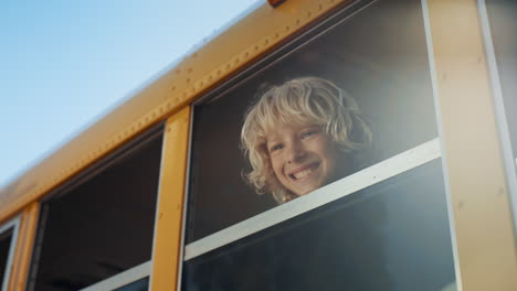Lächelnder-Junge,-Der-Aus-Der-Nähe-Des-Schulbusfensters-Schaut.-Student-Steht-Im-Fahrzeug.