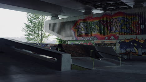 Nobody-at-skate-park-with-colorful-graffiti-on-wall.-Empty-skatepark-ramp.