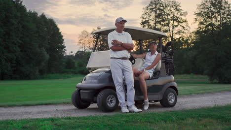 Couple-posing-golf-cart-outside.-Two-golfers-take-clubs-sport-equipment-on-field