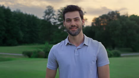 Happy-model-smiling-outside.-Handsome-sportsman-standing-on-golf-course-sunset.