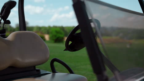 Golf-cart-driving-seat-at-country-club-meadow.-Sport-equipment-by-car-wheel.