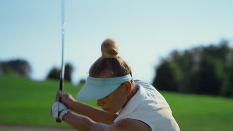 Confident-woman-playing-golf-on-fairway.-Golfer-swinging-ball-at-country-club.