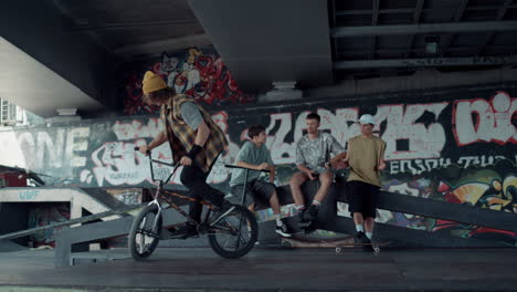 Sporty-man-performing-jump-trick-on-bmx-bike-at-skate-park-with-graffiti.