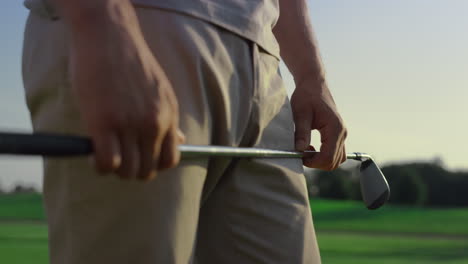 Golfer-hands-holding-putter-on-sunset-course-field.-Man-enjoy-golf-outdoors.