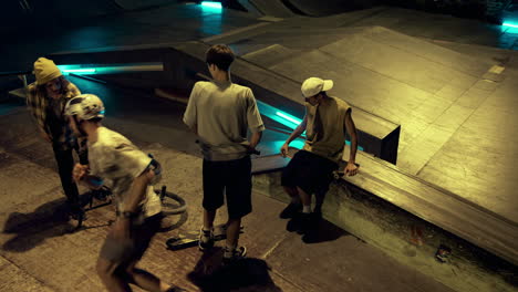 Young-people-finishing-sport-training-at-night-skate-park.-Teens-saying-goodbye